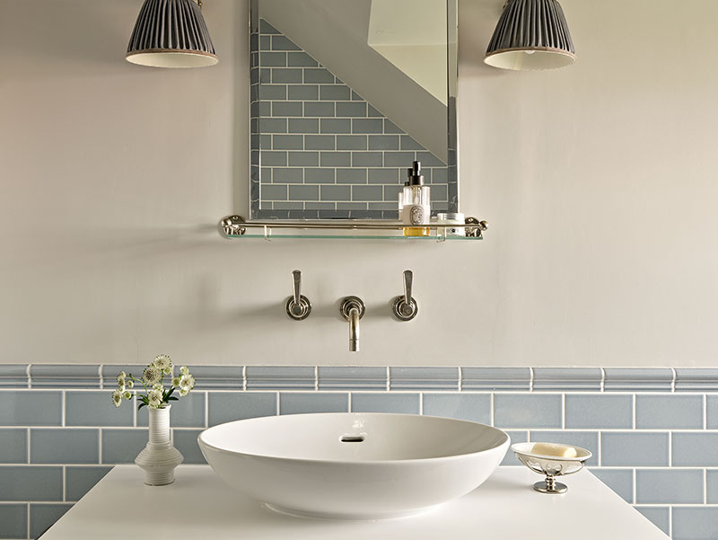 Elegant en-suite basin with soft-toned tiles, minimalist tap, and mirror with built-in shelf