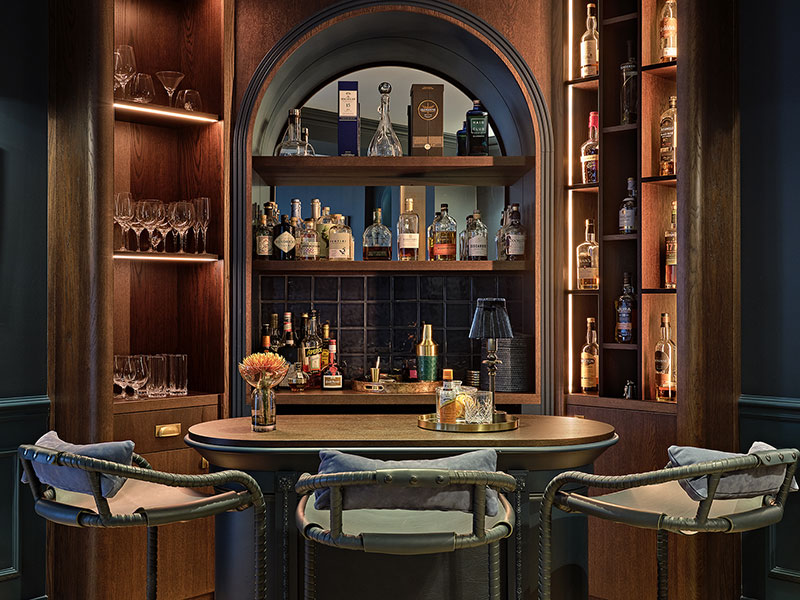Bespoke home bar designed in rich dark wood and inky blues, with custom shelving and backlighting